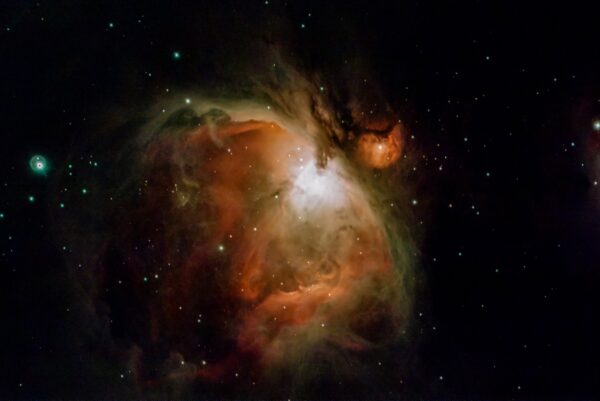 "Orion Nebula" 1500 light years away.The red hue is caused by hydrogen radiation, the green hue was a puzzle for astronomers, initially was named as the new element 'Nebulum",later it was determined ,it is caused by electron transition in ionized oxygen.This radiation was all but impossible to reproduce in the laboratory,it only happens in deep space.